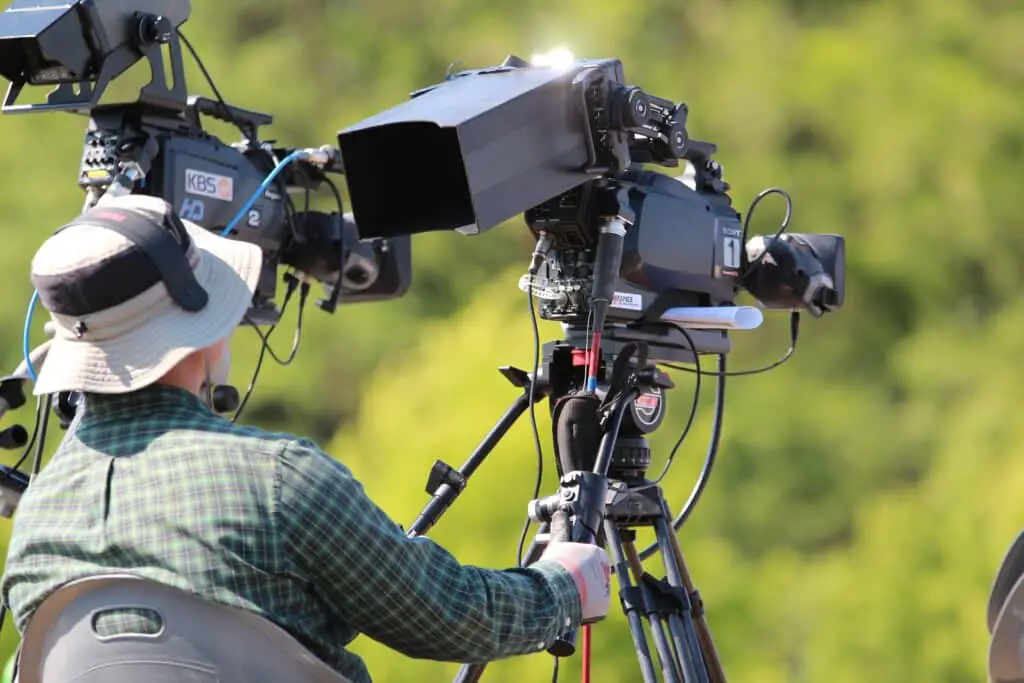 A videographer filming a Kodiak bear in the wilderness.